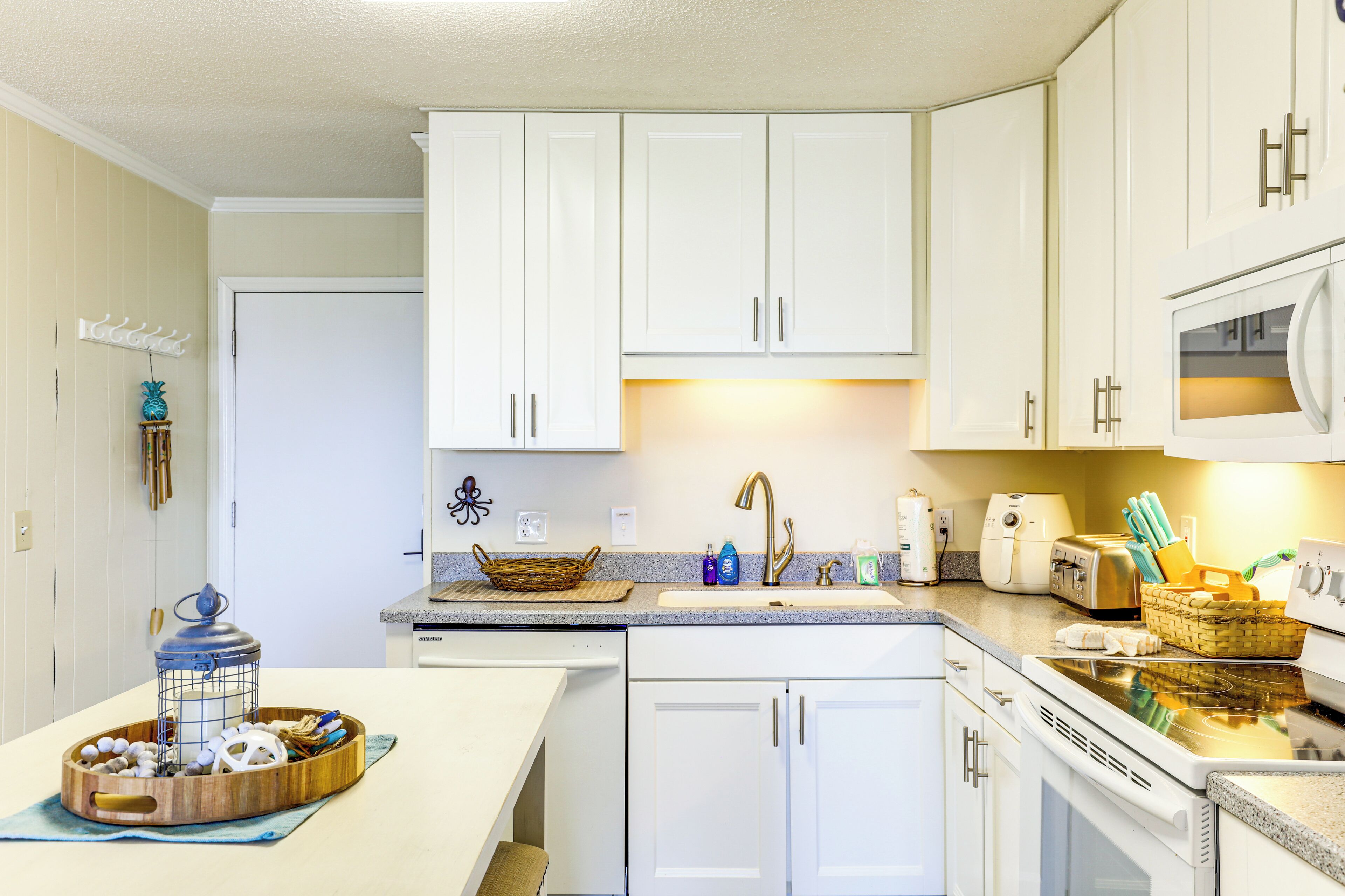 A kitchen with white cabinets, a microwave, a toaster, and a sink.