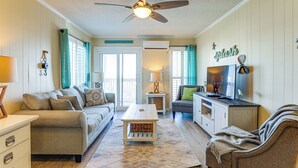 A living room with a ceiling fan, a sofa, a coffee table, and a television on a cabinet. - Steps to Sea! 3rd-floor Myrtle Beach Condo w/ Pool (Myrtle Beach)