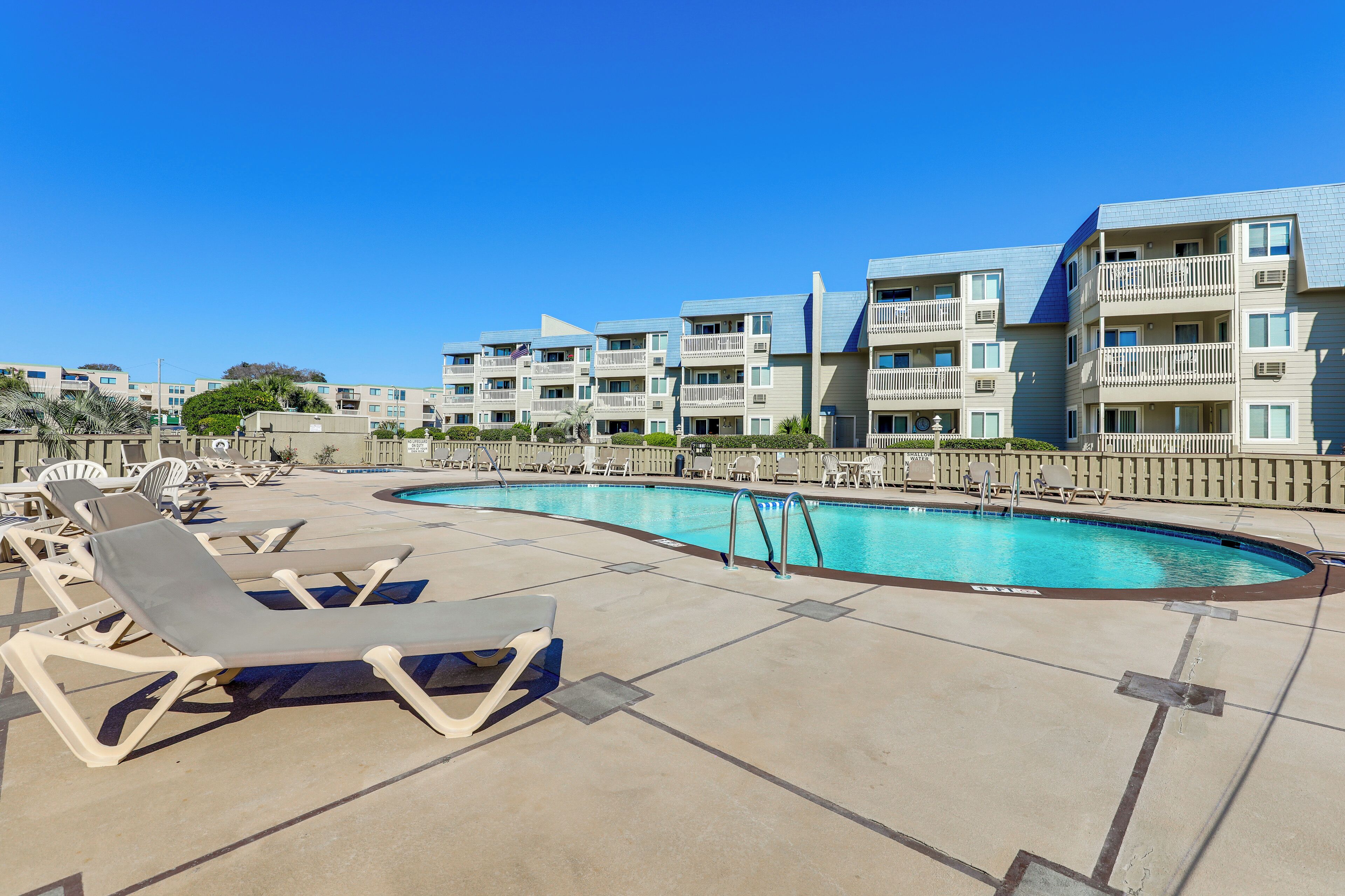 A pool area with lounge chairs and a swimming pool surrounded by multi-story buildings.