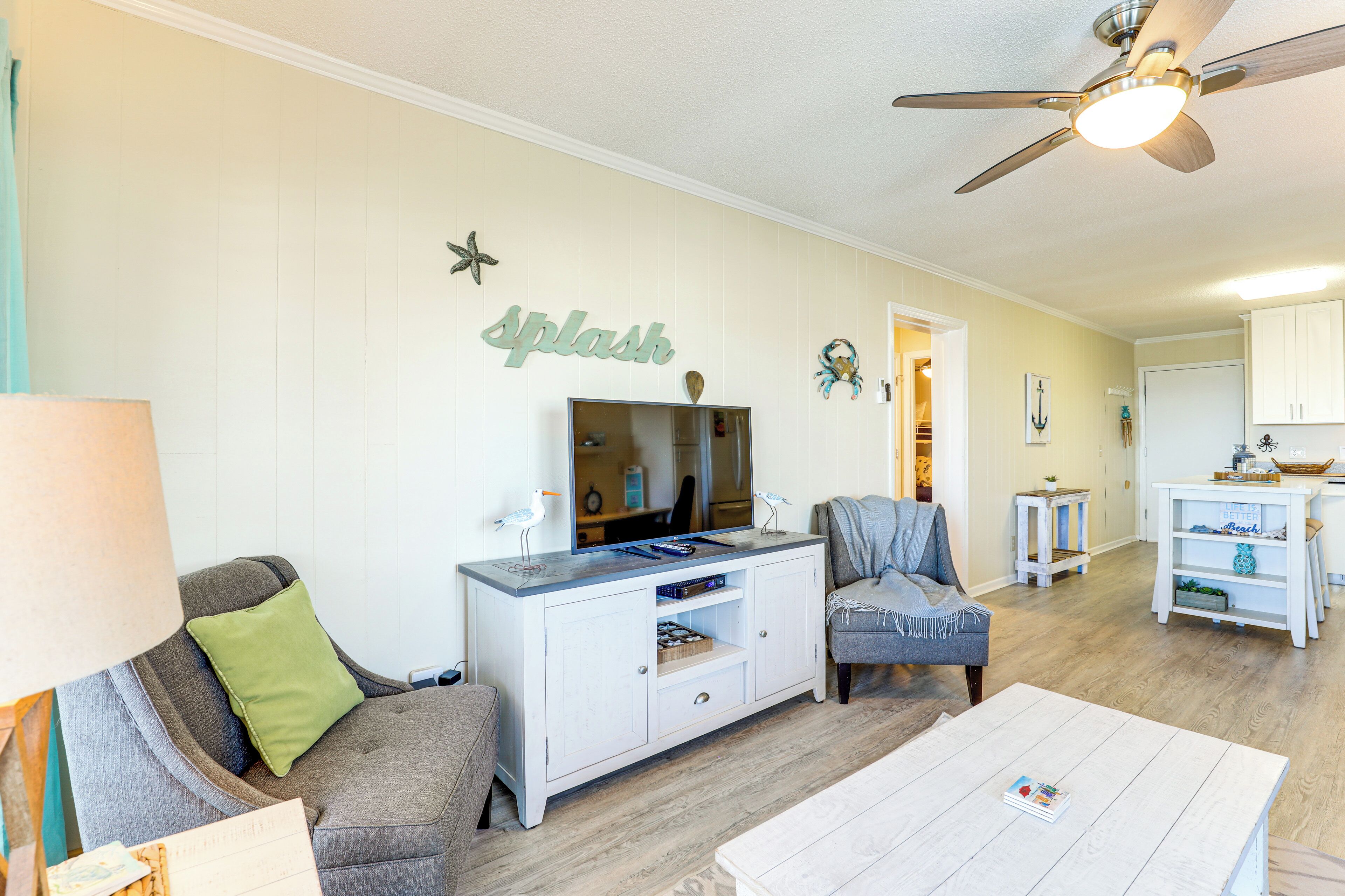 A living room with a sofa, a coffee table, a TV, and a ceiling fan.