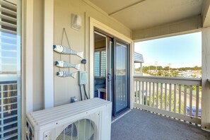 Een balkon met uitzicht op een woongebied, een witte airconditioning en decoratieve vissen aan de muur.