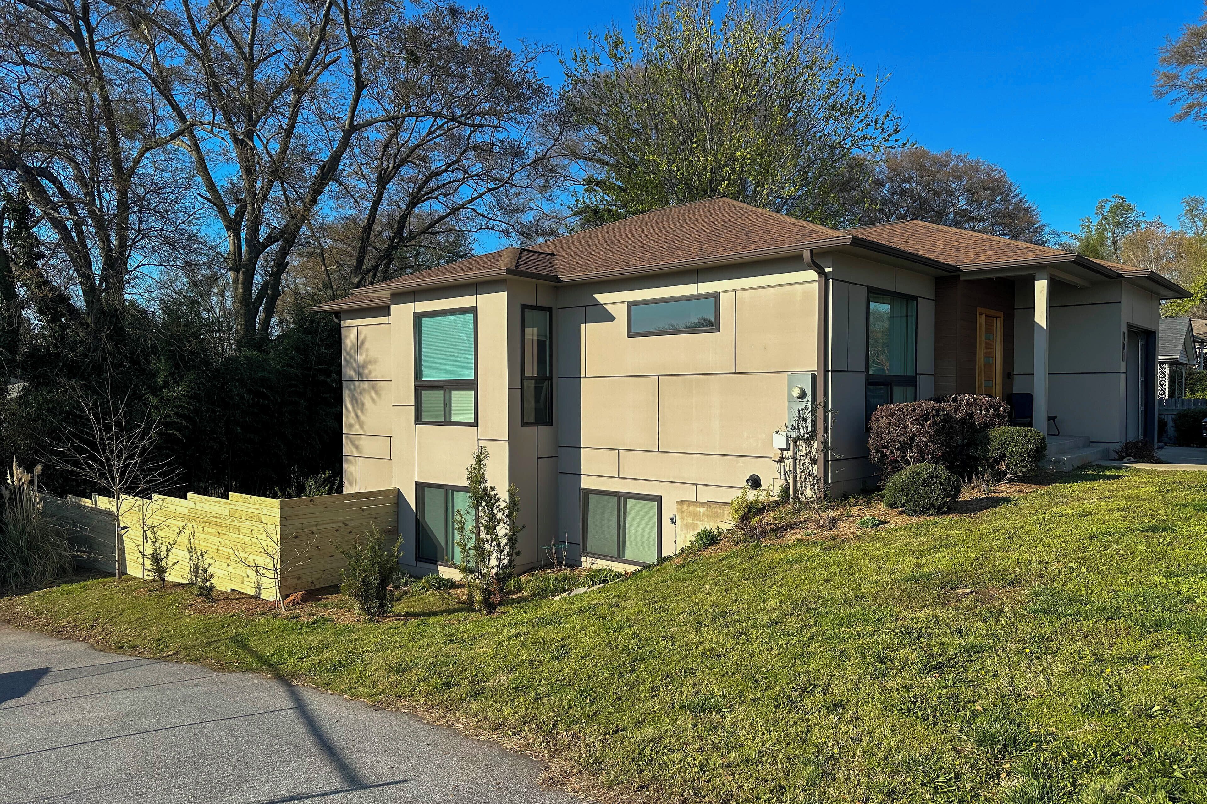 A modern two-story house with a sloped roof, large windows, and a well-maintained lawn.