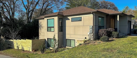 A modern two-story house with a sloped roof, large windows, and a well-maintained lawn.