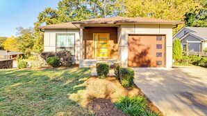 Ein eingeschossiges Haus mit Veranda, Garage und gepflegtem Rasen.