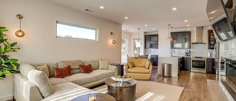 A modern living room with a sofa, coffee table, and a dining area with a chair.