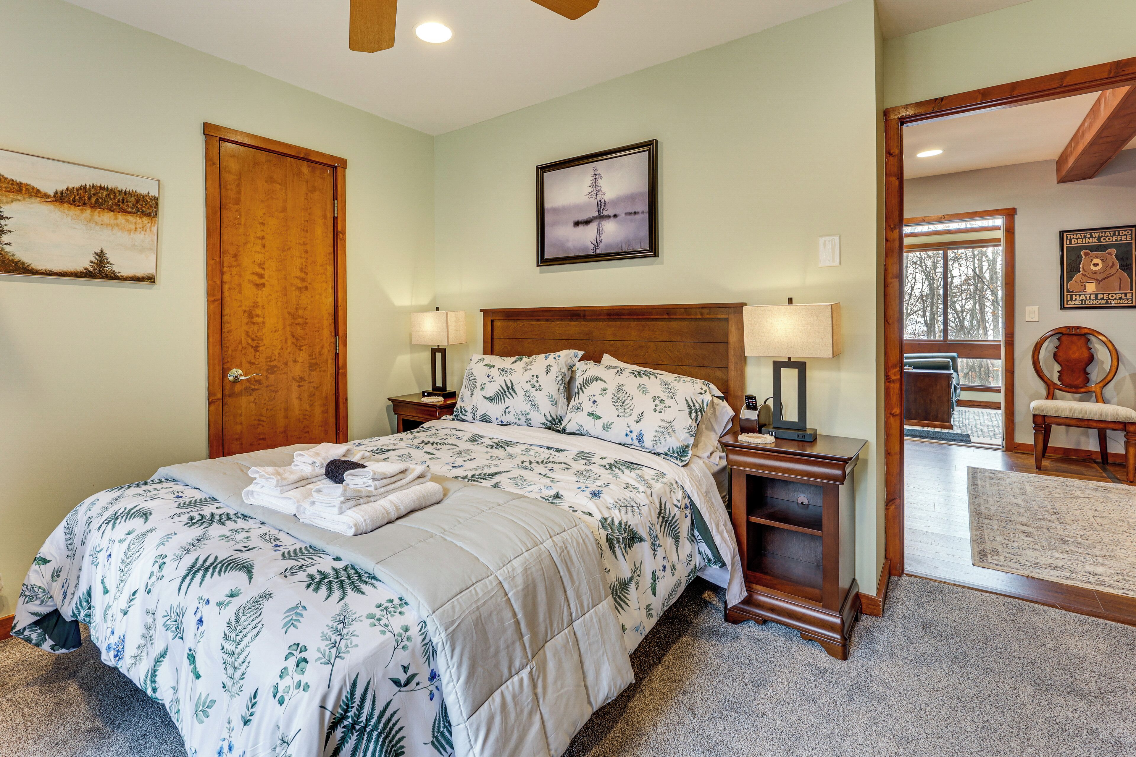 Une chambre à coucher avec un lit, des tables de chevet, une commode, un miroir et une porte.