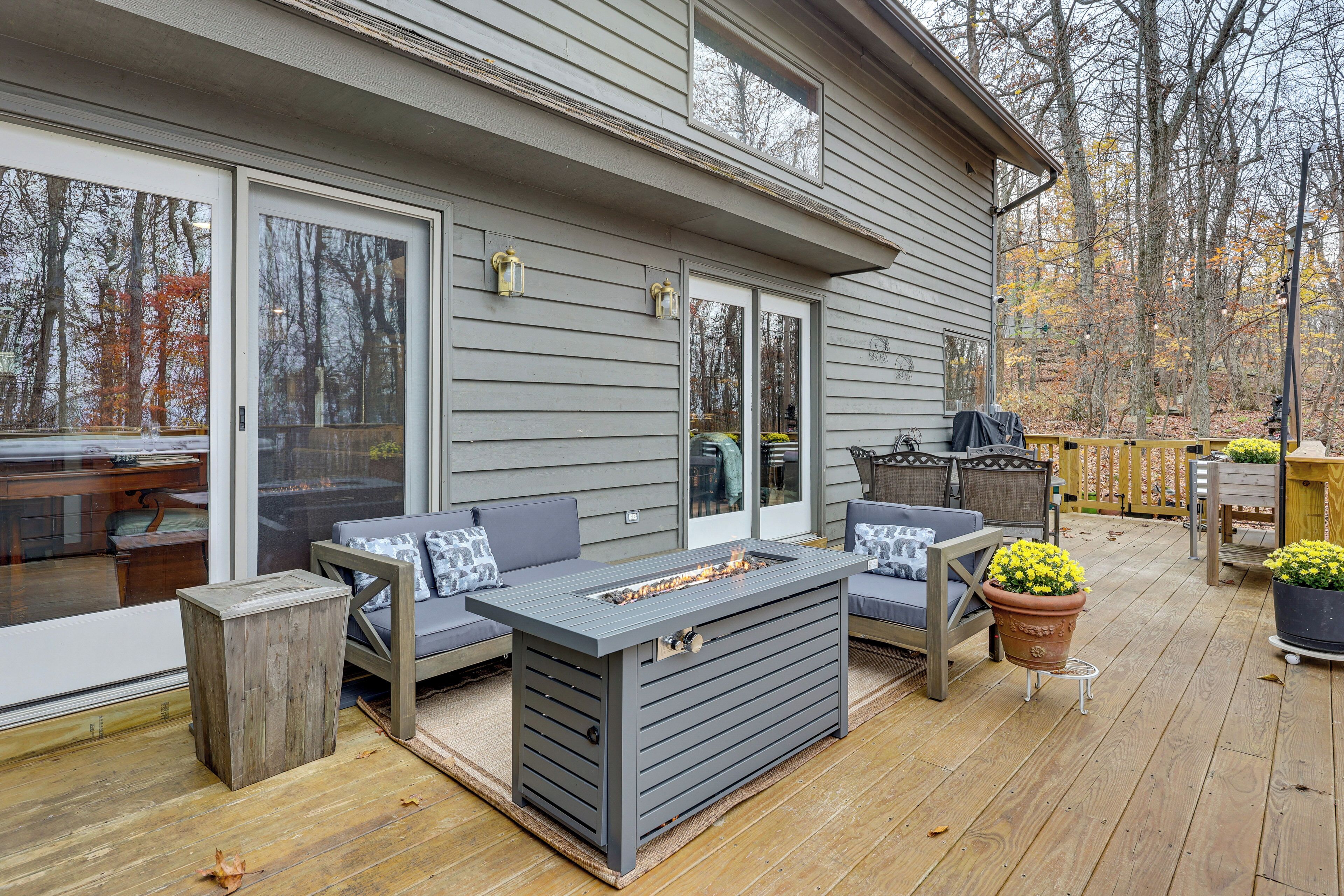 A deck with outdoor furniture, including a gray table and two gray sofas with pillows.
