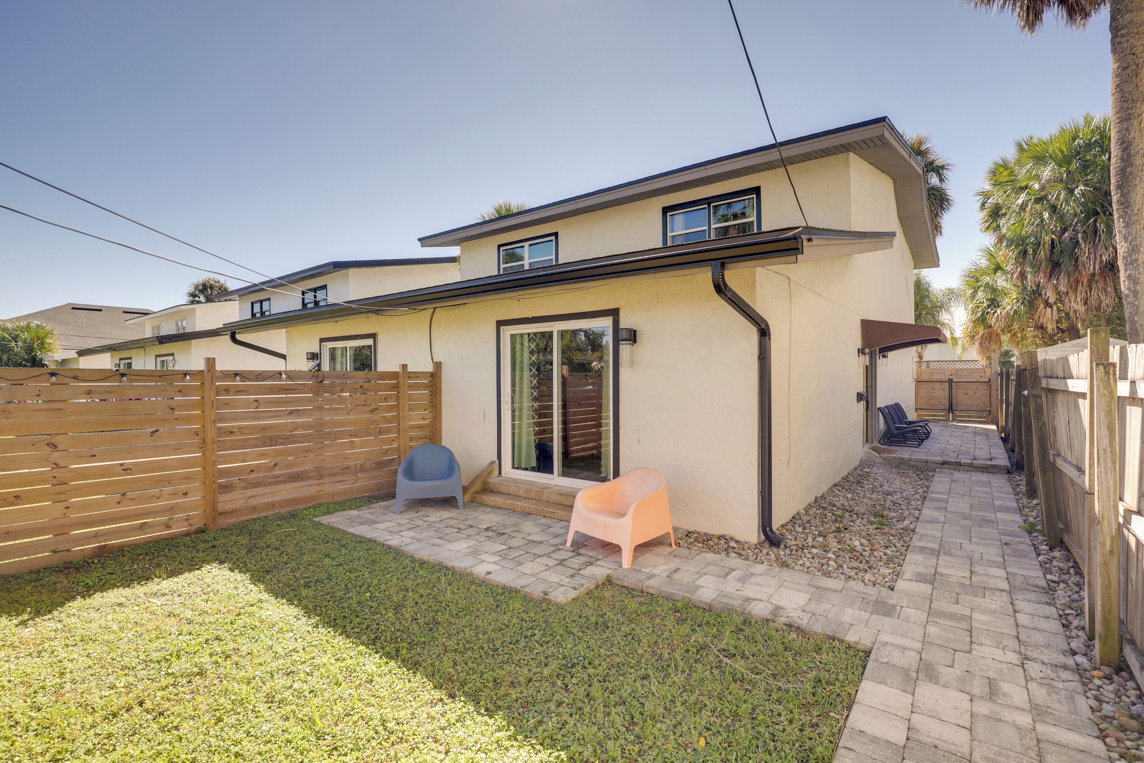 A two-story house with a patio area, a wooden fence, and a small garden.