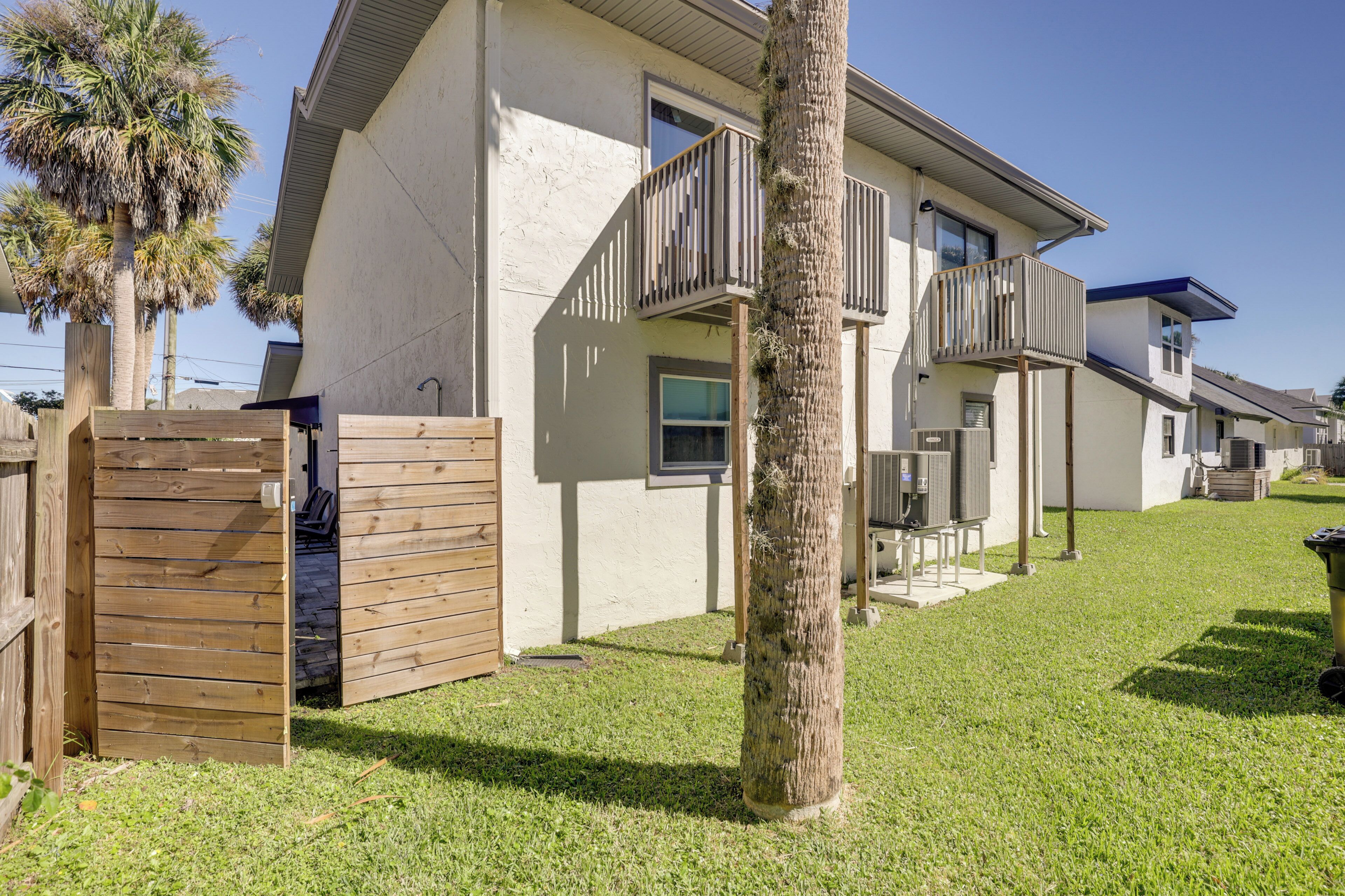 A residential building with a wooden gate, a palm tree, and a clear sky.