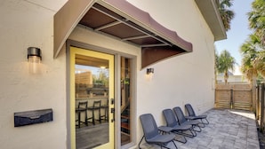 Une terrasse avec des sièges extérieurs et une porte-fenêtre coulissante donnant sur un espace intérieur.