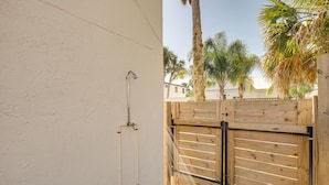 Une clôture en bois avec un portail en métal, un tuyau d’eau et un mur avec une conduite.