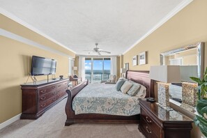 Une chambre avec un grand lit, une commode, une télévision et un balcon avec vue.
