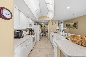 A kitchen with white cabinets, a microwave, a coffee maker, and a sink. - 701 Twin Towers in Daytona Beach Shores, FL (Daytona Beach Shores)