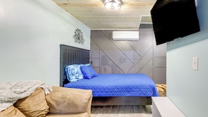 Ein Schlafzimmer mit Bett, Sofa, Fernseher und Deckenleuchte.