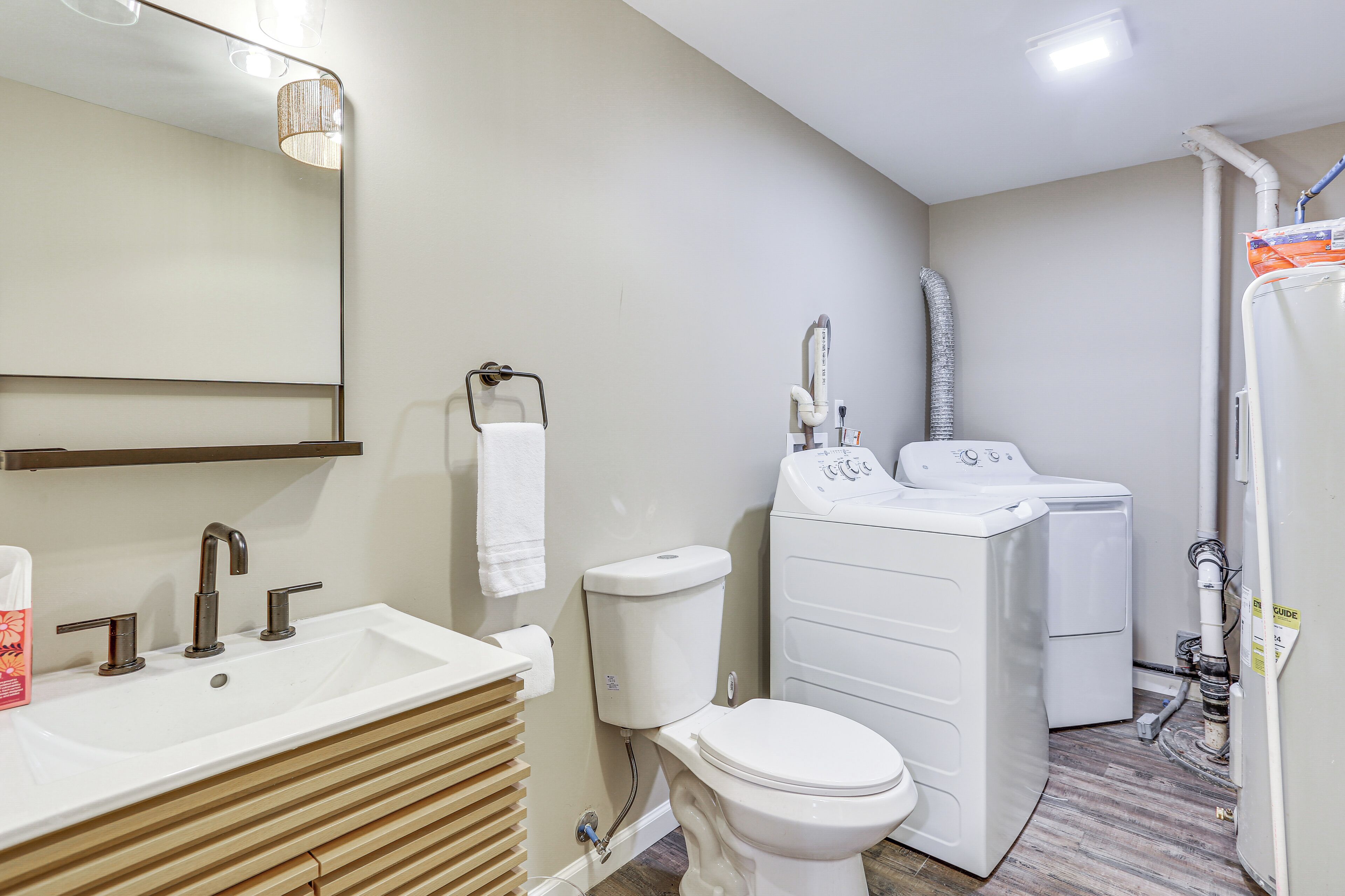 A bathroom with a sink, toilet, and washing machine.