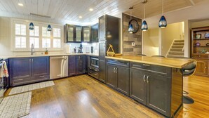 Una cocina moderna con armarios oscuros, una isla de madera e iluminación colgante.