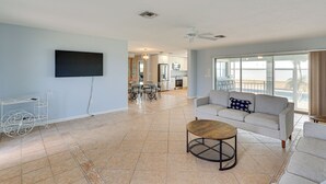 Een ruime woonkamer met een flatscreen televisie, een bank, een salontafel en een eettafel met stoelen.