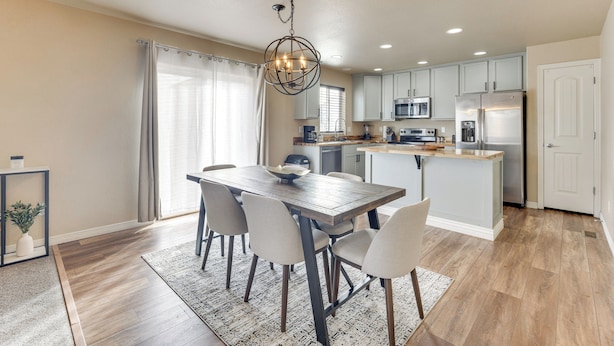 Een moderne keuken met een centraal eiland, inbouwapparatuur en een eethoek met een houten tafel en stoelen.