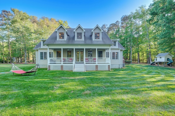 A large, two-story house with a porch, surrounded by a well-maintained lawn and trees.
