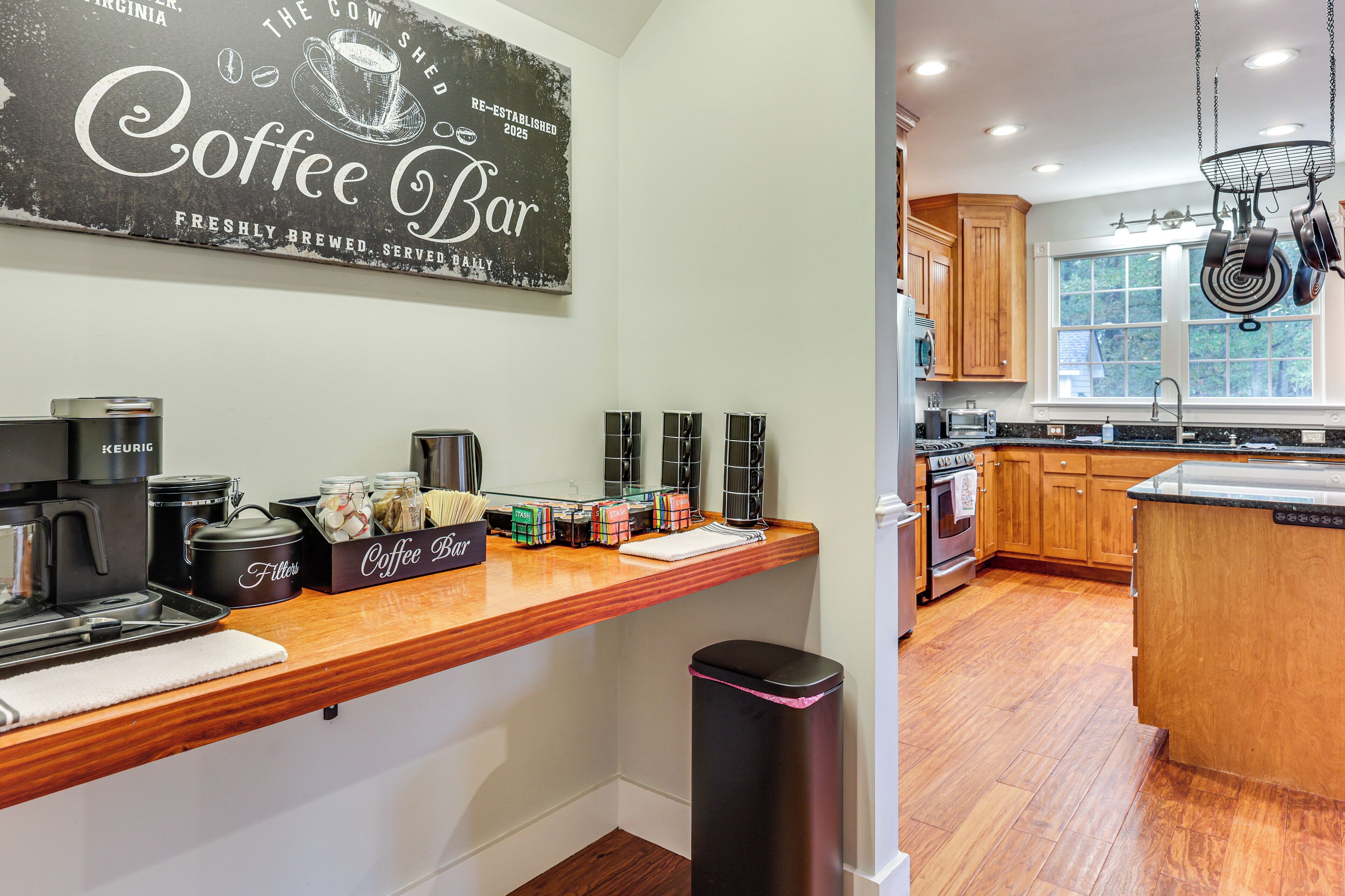 A kitchen with wooden cabinets, a coffee bar, and a window with a view.