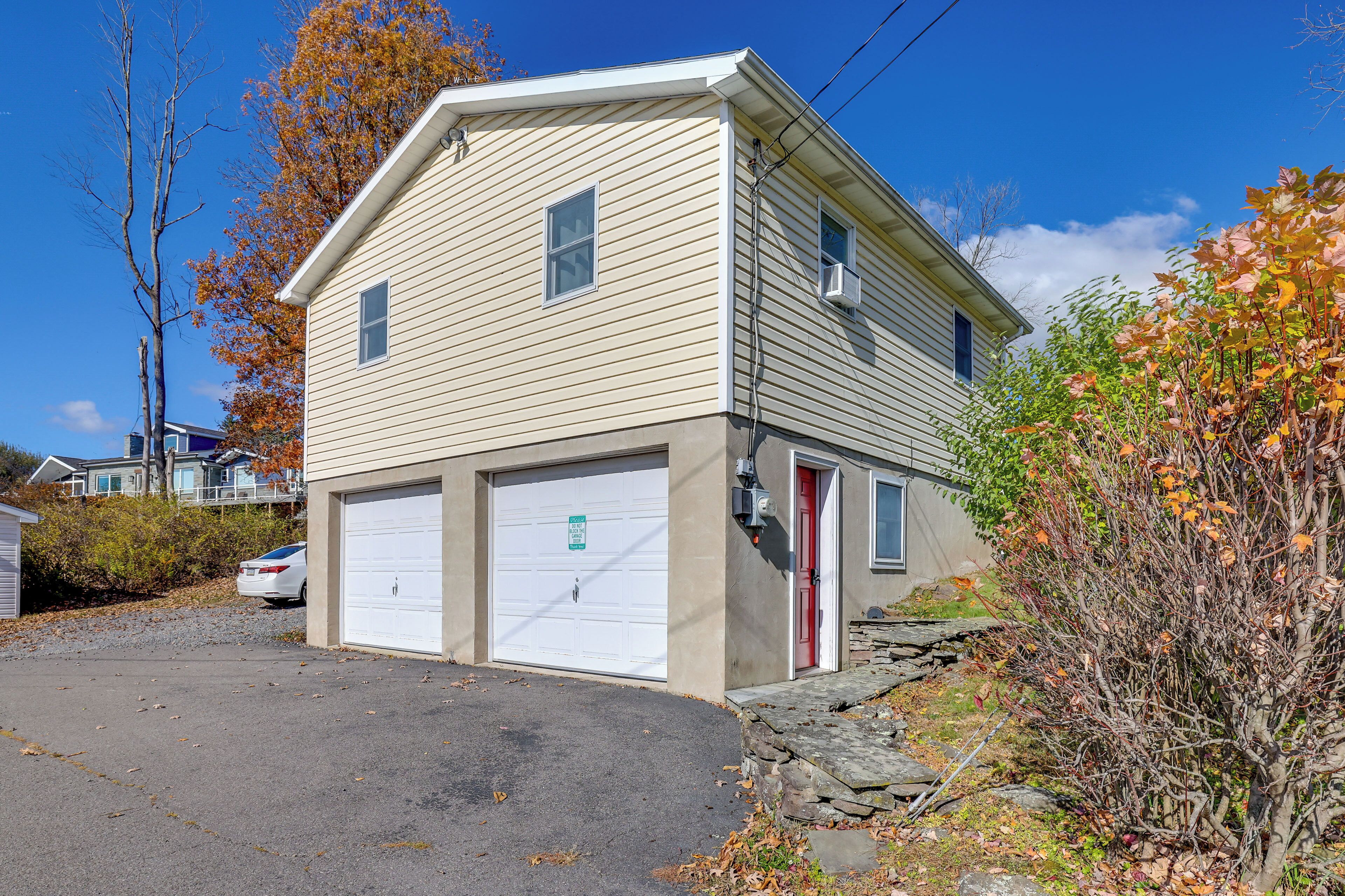 A two-story house with a garage, a red door, and a driveway.