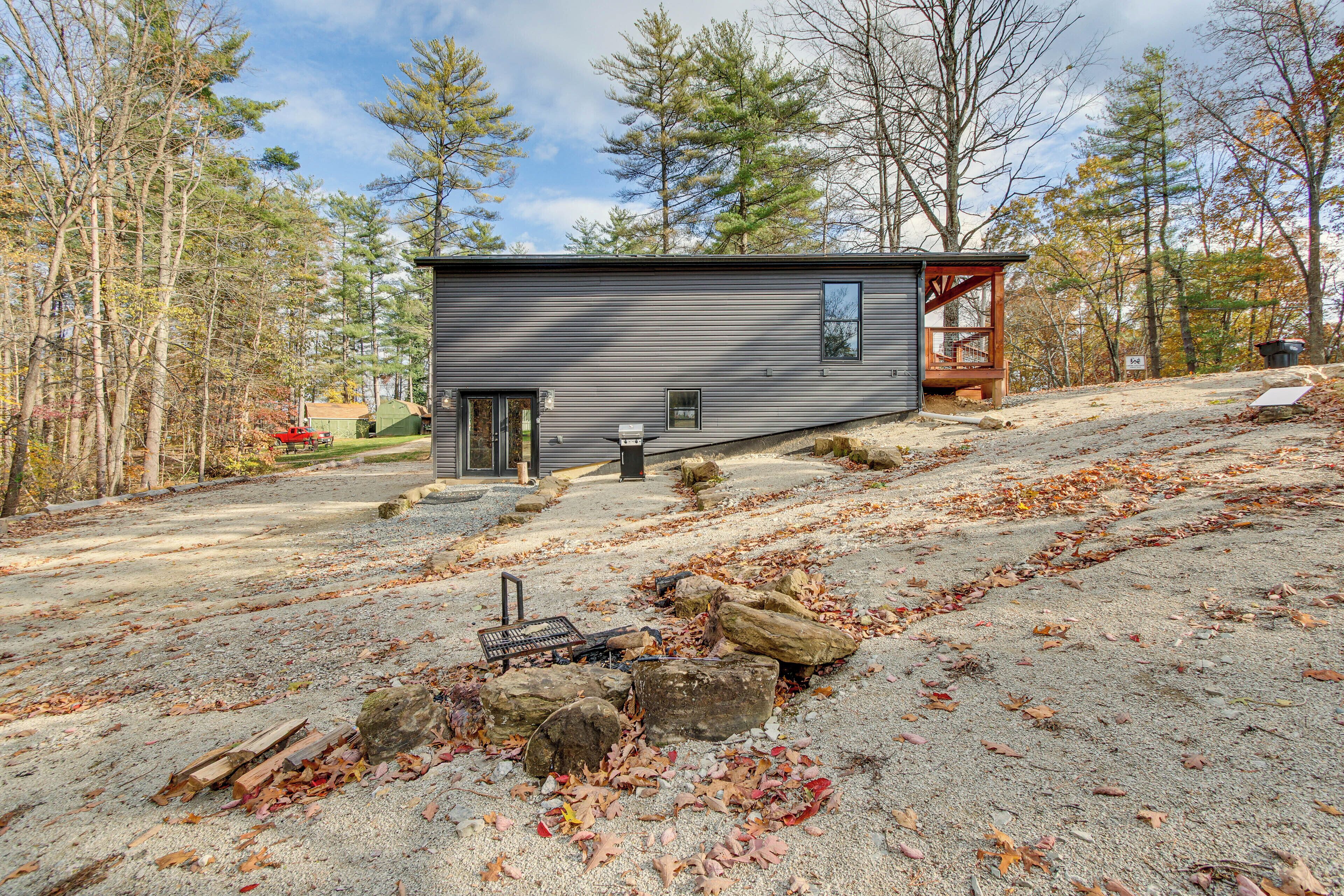 A modern cabin with a deck, surrounded by a forested area.