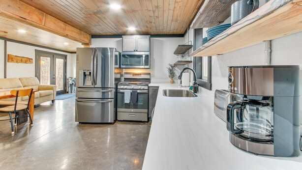 A modern kitchen with stainless steel appliances, a white countertop, and wooden ceiling beams. - 'chène Cottage' Near Burr Oak Lake & Trailheads! (Glouster)