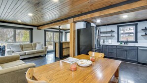 A spacious living area with a wooden ceiling, a large dining table, and a sofa. - 'chène Cottage' Near Burr Oak Lake & Trailheads! (Glouster)