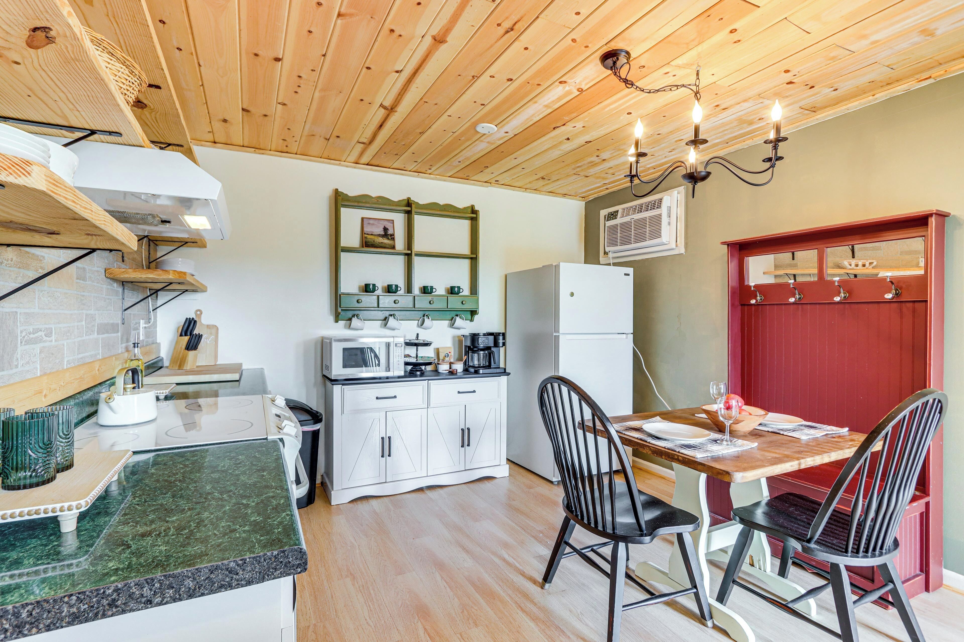 Una cocina con techo de madera, armarios blancos y un armario rojo, además de una mesa de comedor con sillas.