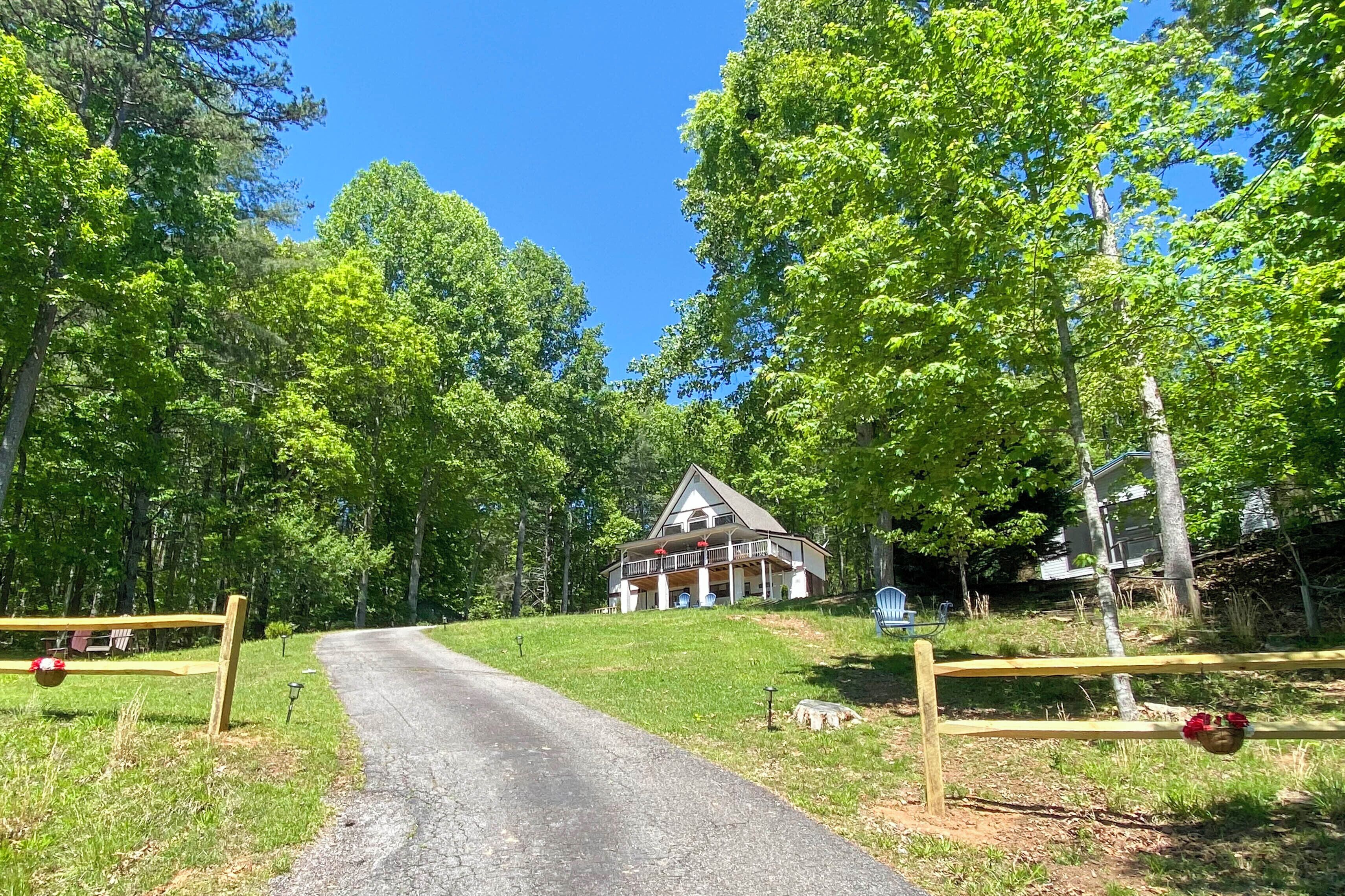 A house with a porch, surrounded by trees and a gravel driveway.