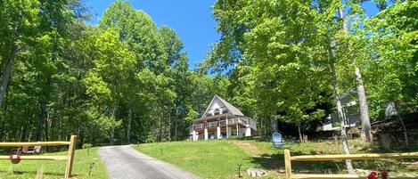 A house with a porch, surrounded by trees and a gravel driveway.