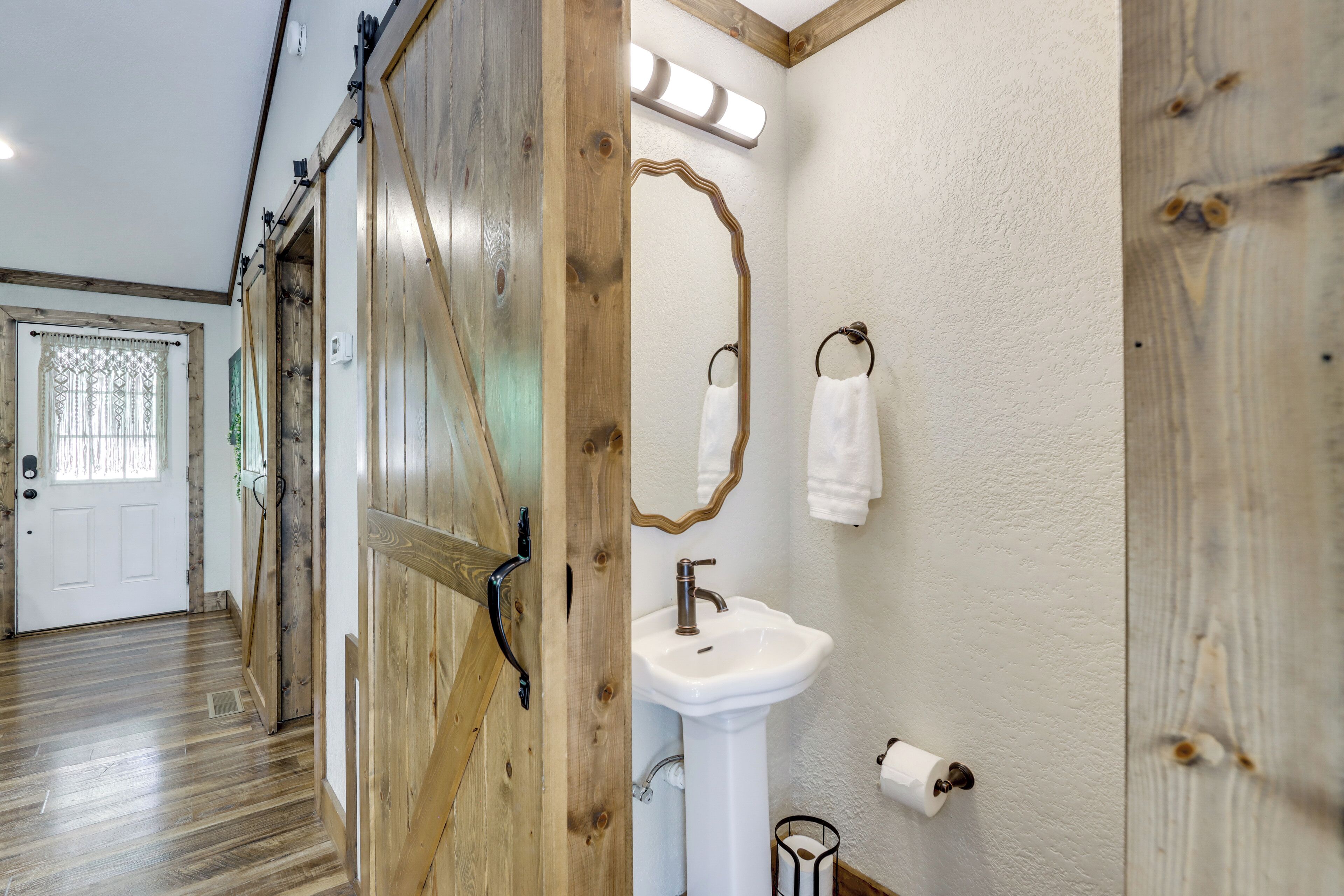 A wooden door with a mirror and a white sink in a hallway.