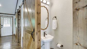 A wooden door with a mirror and a white sink in a hallway.