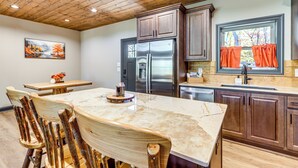 A kitchen with wooden cabinets, a stainless steel refrigerator, and a marble countertop. - New Build! Secluded Mountain Home in Murphy (Murphy)