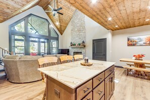 A spacious living area with a large island, wooden ceiling, and a stone fireplace. - New Build! Secluded Mountain Home in Murphy (Murphy)