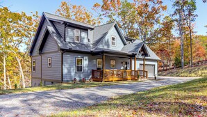 A two-story house with a front porch, garage, and a driveway leading to the entrance. - New Build! Secluded Mountain Home in Murphy (Murphy)