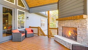 A deck with wicker furniture and a stone fireplace. - New Build! Secluded Mountain Home in Murphy (Murphy)