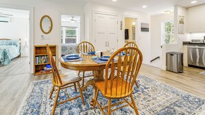 A dining area with a round wooden table, four chairs, and a blue patterned rug.