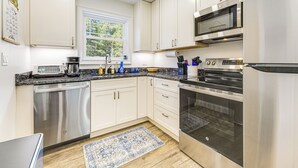 A modern kitchen with stainless steel appliances, white cabinetry, and a window providing natural light.