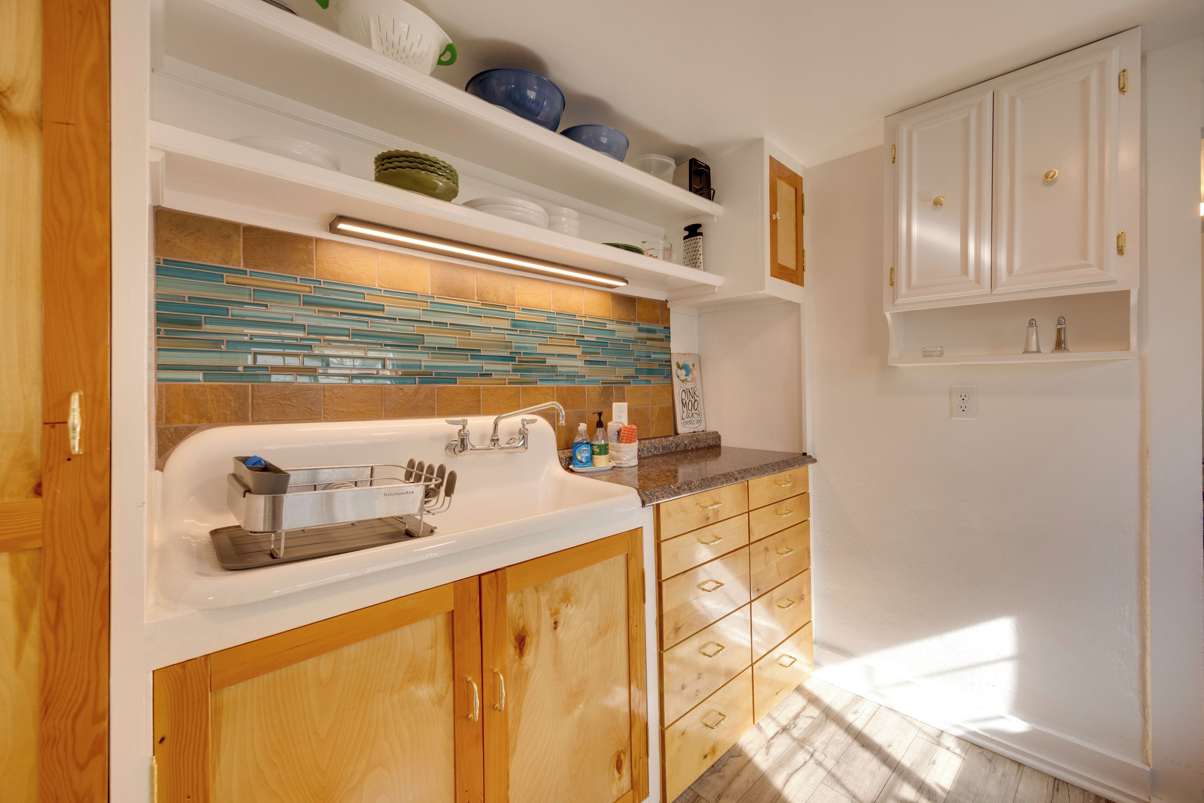 Una cocina con armarios de madera, encimera blanca y salpicadero de azulejos.