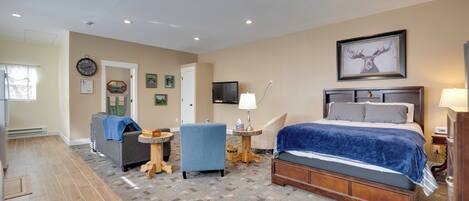 A bedroom with a bed, a chair, a small table, and a television.