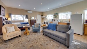 A spacious living area with a sofa, armchair, and a small side table. A washing machine and a refrigerator are visible in the background. - Cozy Couple's Retreat 5 Mi to Garden of the Gods! (Colorado Springs)