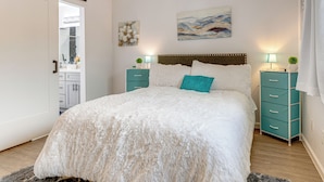Une chambre à coucher avec un grand lit, deux tables de chevet, une tête de lit et un tableau au mur.