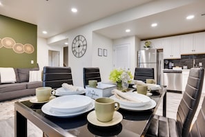 A modern kitchen with a dining area, featuring a clock, a refrigerator, and a coffee table with plates and cups. - 8 Mi to Usafa! Hot Tub Haven in Colorado Springs (Colorado Springs)