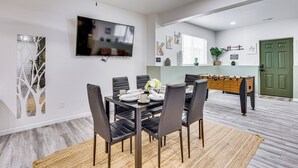 Un comedor con una mesa dispuesta para seis personas, un ventilador de techo y un televisor montado en la pared.