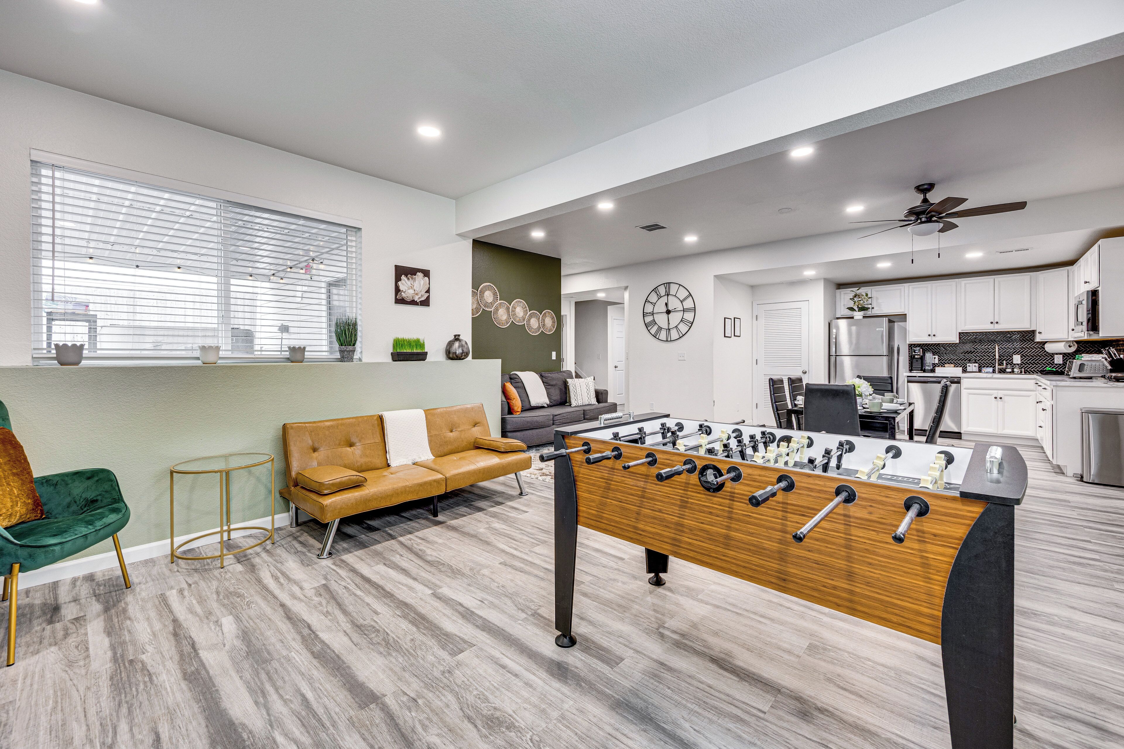 A modern living room with a foosball table, a sofa, and a green chair.