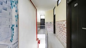 A hallway with a brick wall, a door labeled '203', and a staircase with a metal railing. - Hotel Kuber 7 (Zirakpur)