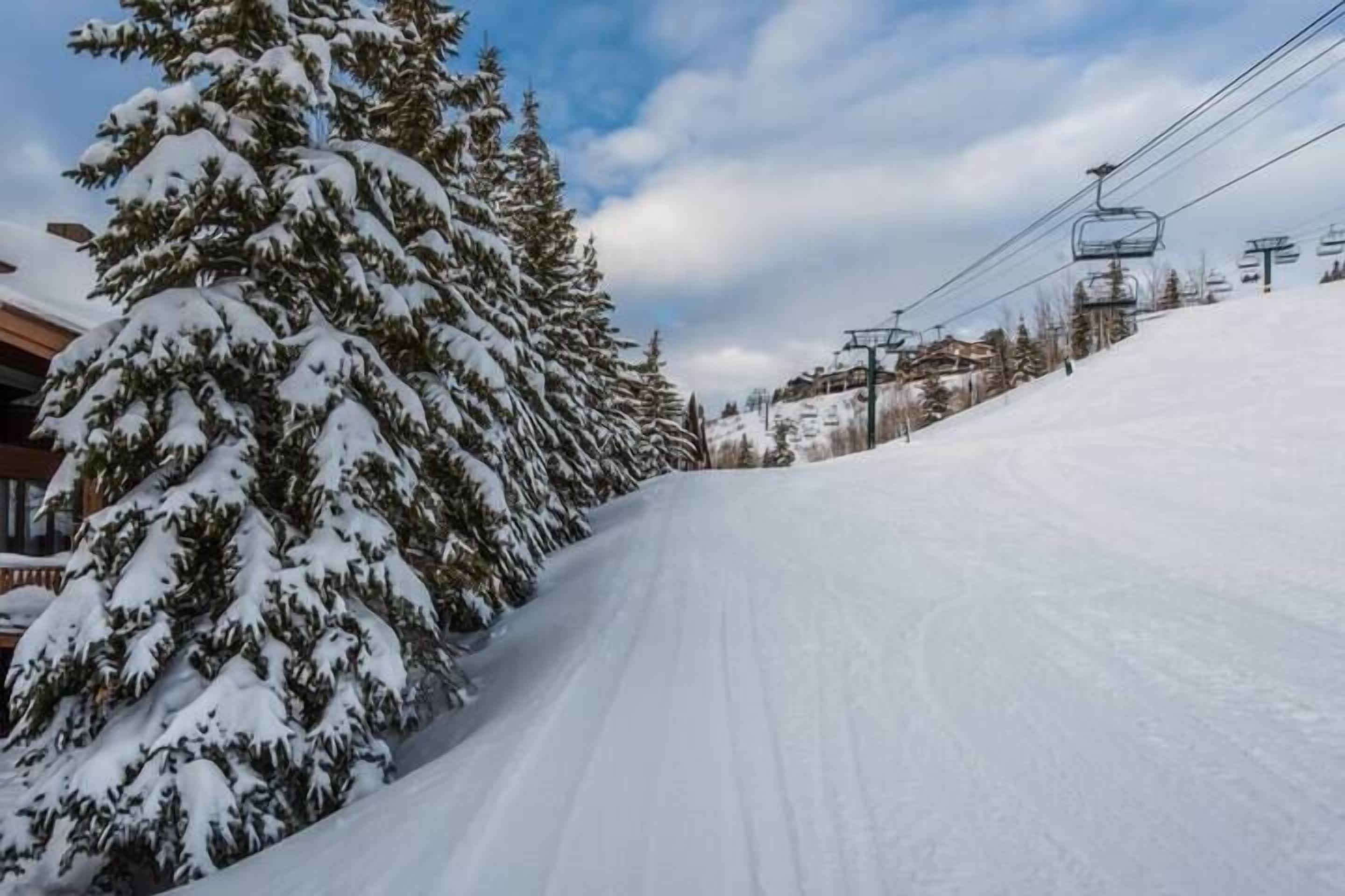 Une piste de ski enneigée, avec un télésiège et des bâtiments en arrière-plan.