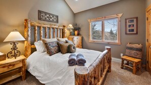 A bedroom with a wooden bed frame, white bedding, and a small wooden nightstand with a lamp. - Timberwolf Canyons Village, 3BR, sleeps 6, hot tub (Park City)