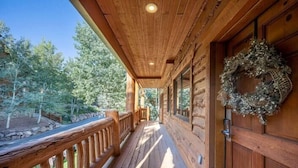 A wooden cabin with a porch, a wooden door with a wreath, and a view of trees. - Timberwolf Canyons Village, 3BR, sleeps 6, hot tub (Park City)